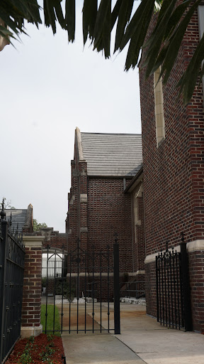A glimpse of a historic brick building, showcasing intricately designed architecture against a gray sky.