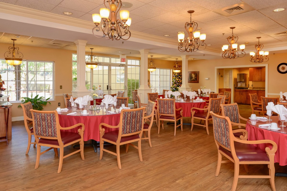 An elegant dining room with neatly arranged tables and chandeliers.