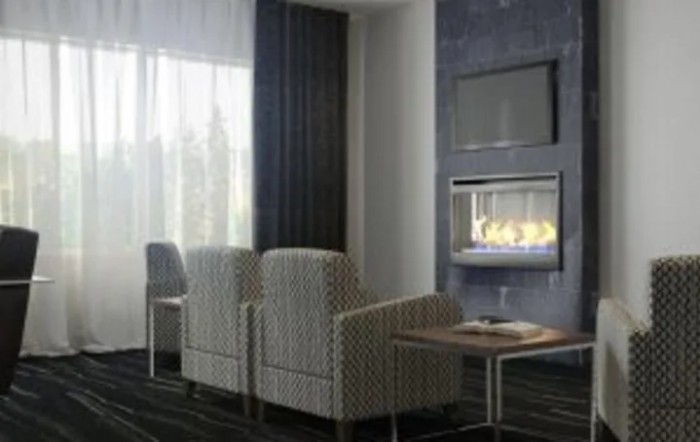 A modern living room with cozy chairs facing a fireplace and television.