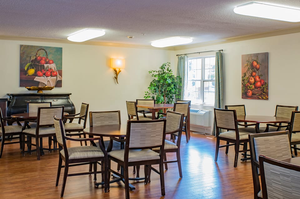 A cozy dining area with several tables and chairs, featuring a piano and decorative wall art.