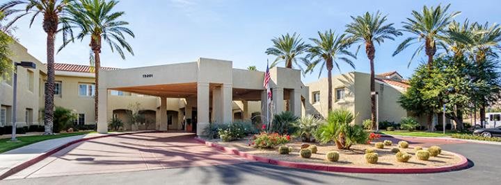 A hotel entrance surrounded by desert landscaping and palm trees.