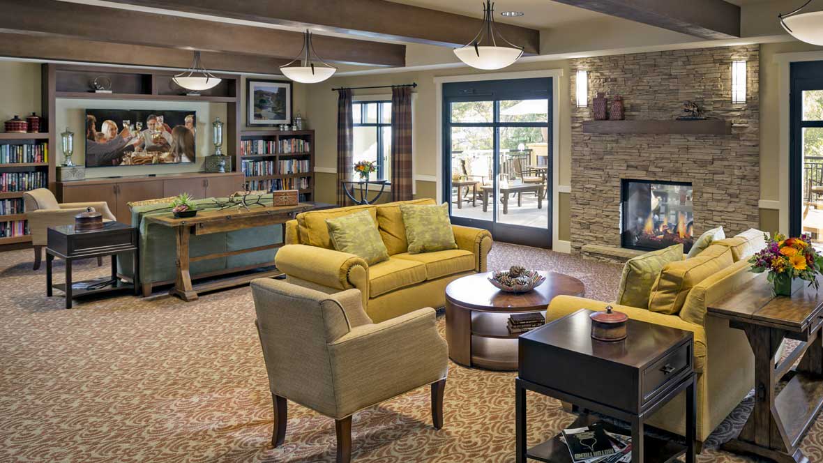 A cozy living room with a yellow sofa, armchair, and a fireplace.