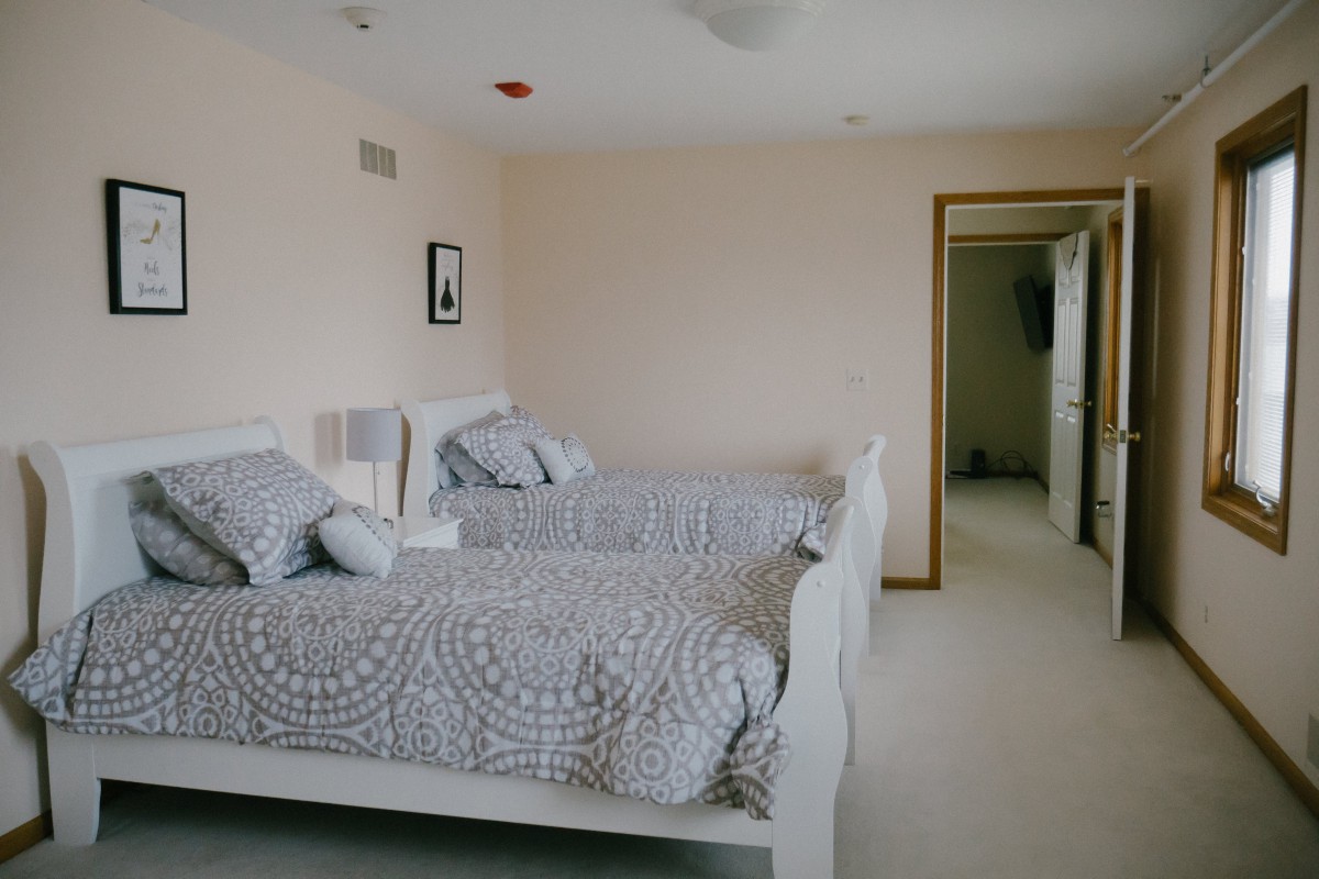 A minimalist bedroom with twin beds and neutral-colored decor.