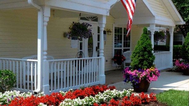 A charming porch adorned with colorful flowers and an American flag.