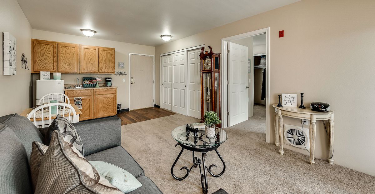 A cozy living space in an apartment with a sofa, coffee table, and open kitchen area.