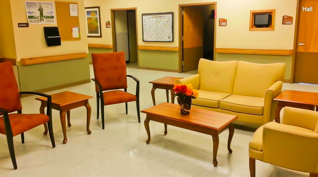 A cozy waiting area with a sofa, chairs, and tables adorned with a flower arrangement.
