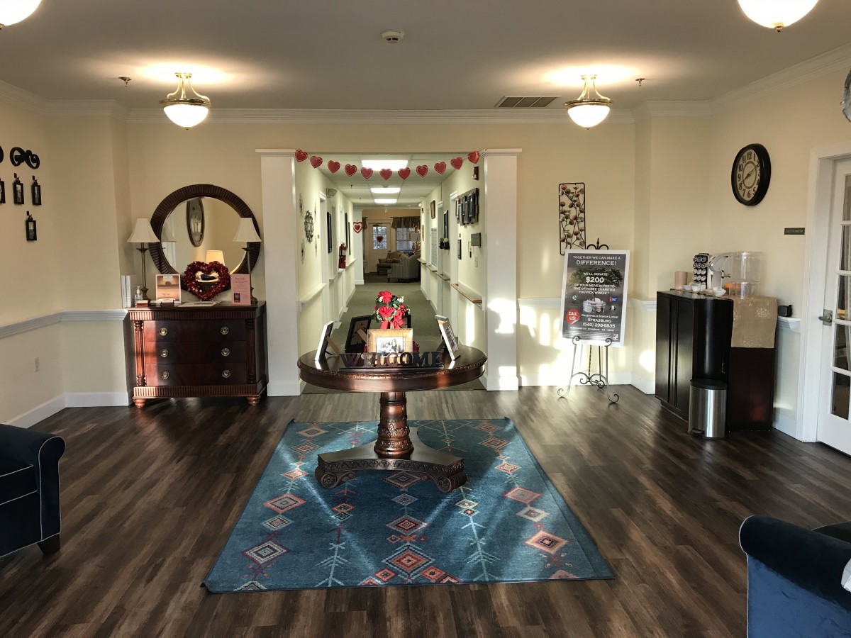 A well-lit interior space with a central table, decorative rug, and hallway leading to other rooms.