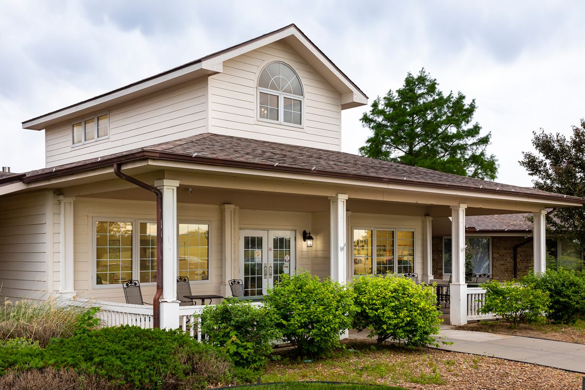 A cozy two-story suburban house with a spacious porch and well-maintained landscaping.