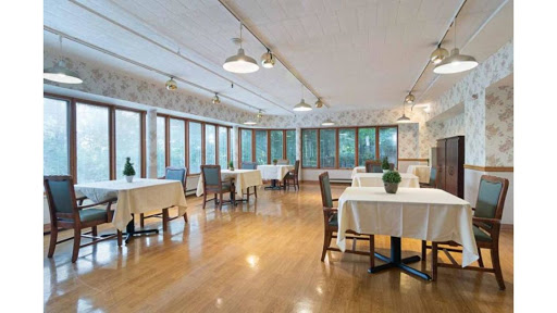 A spacious and well-lit dining area with neatly arranged tables and chairs, featuring large windows that allow for ample natural light.