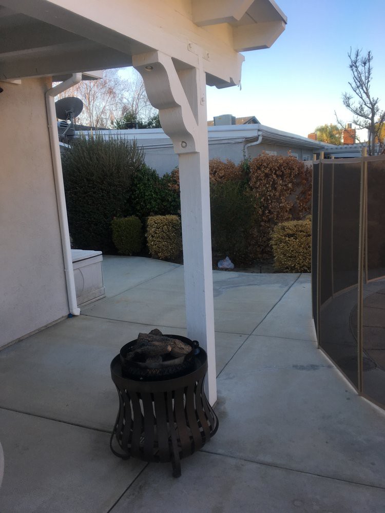 A backyard patio area featuring a fire pit and surrounding bushes.