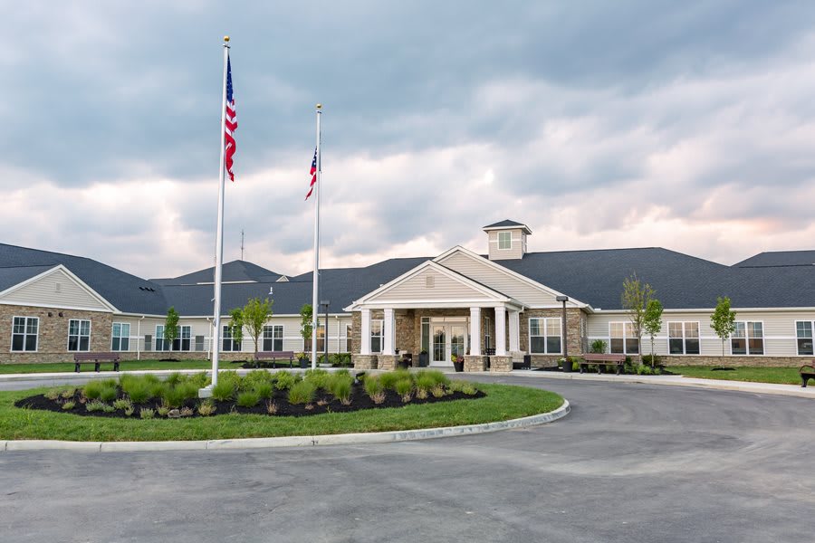 A large building with a grand entrance and flags out front under a cloudy sky.