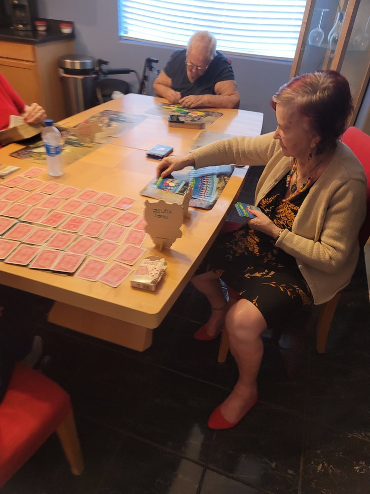 A group of people sitting around a table playing a card game.