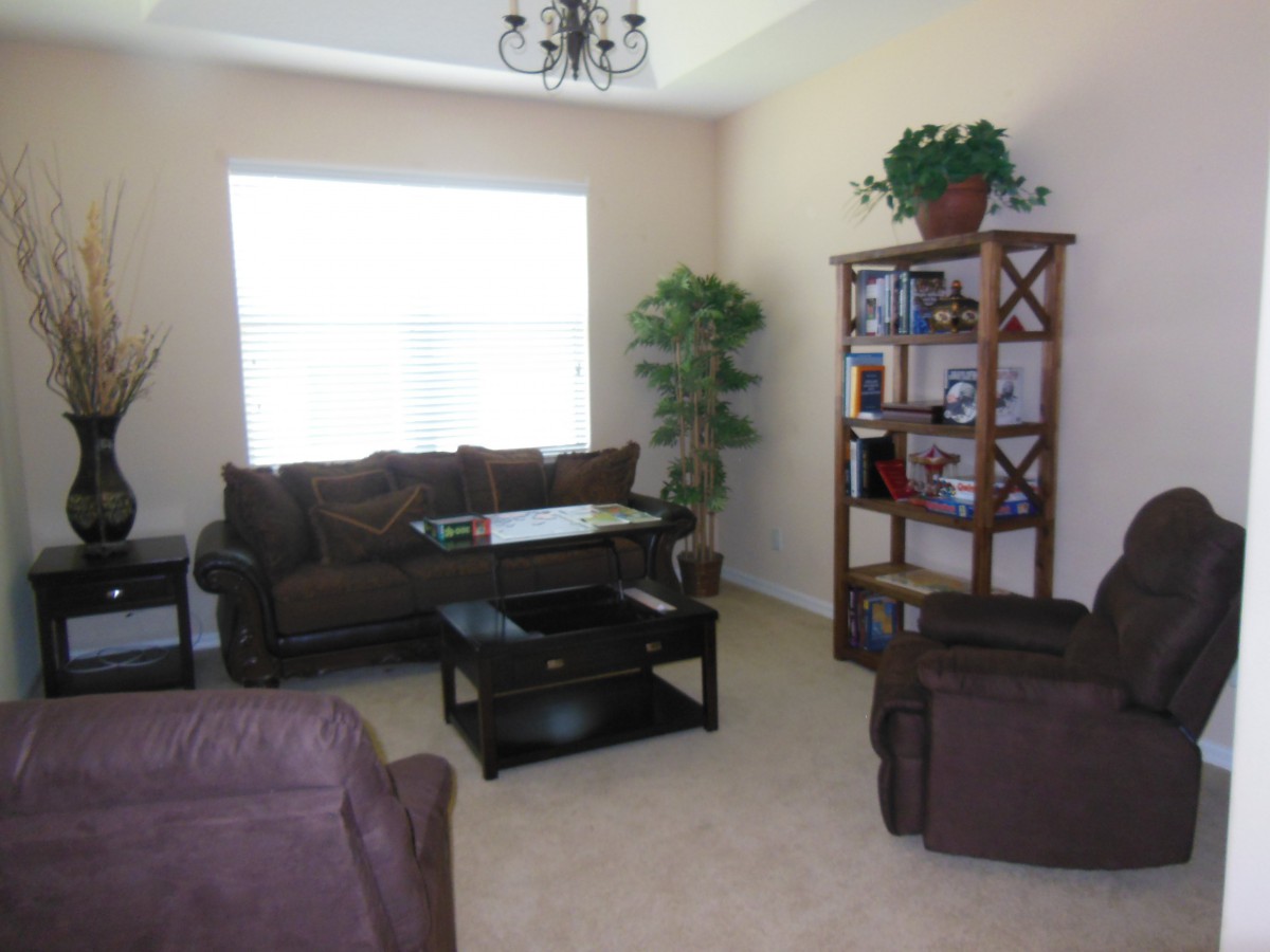 A cozy living room with brown furniture and a large window letting in natural light.