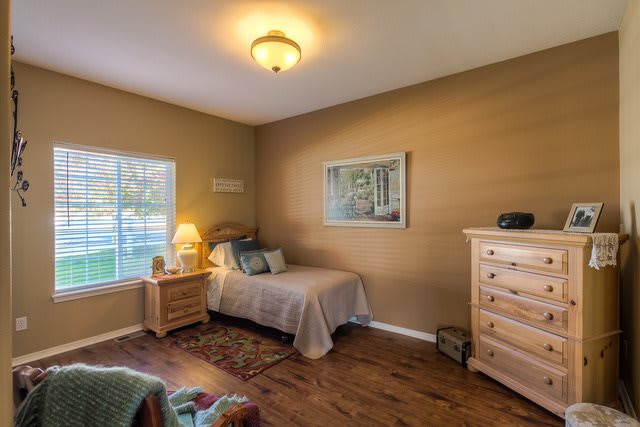A cozy bedroom with a single bed, wooden furniture, and soft lighting.