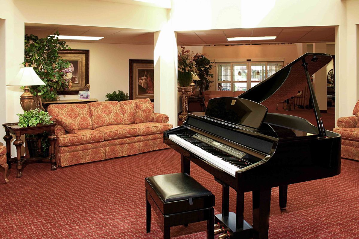 A cozy living room featuring a grand piano and comfortable seating arrangements.