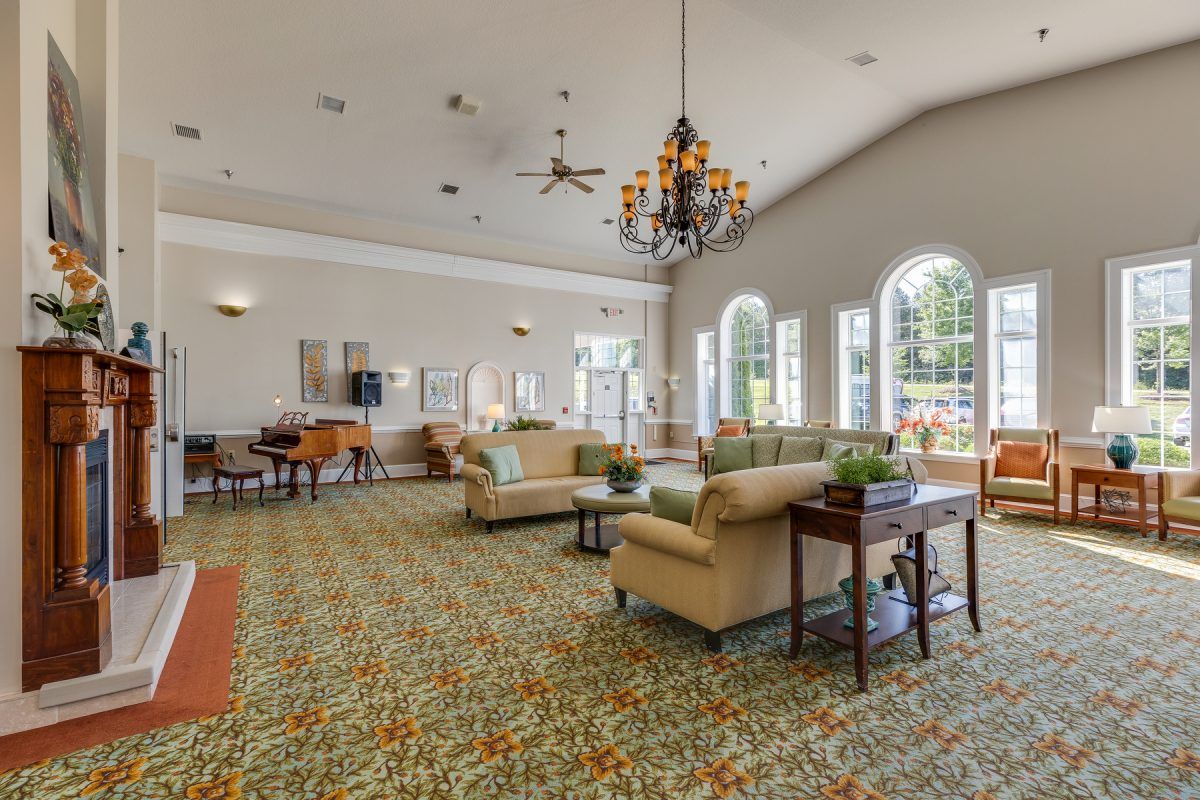 A spacious and well-decorated lounge area featuring comfortable sofas, a chandelier, large windows, and stylish decor.