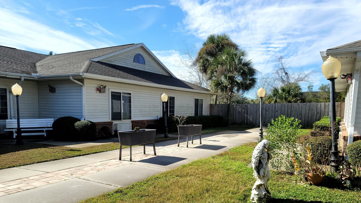 A suburban house with a patio and a well-maintained lawn under a clear blue sky.