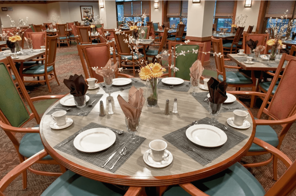 An elegantly set dining table in a restaurant, complete with place settings and floral centerpiece.