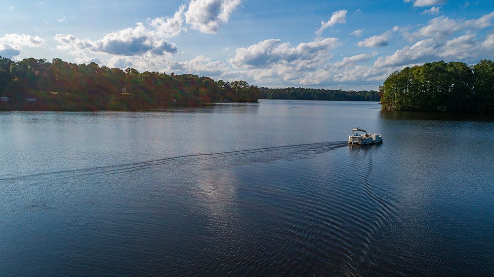 A boat travels across a tranquil lake under a cloudy sky.