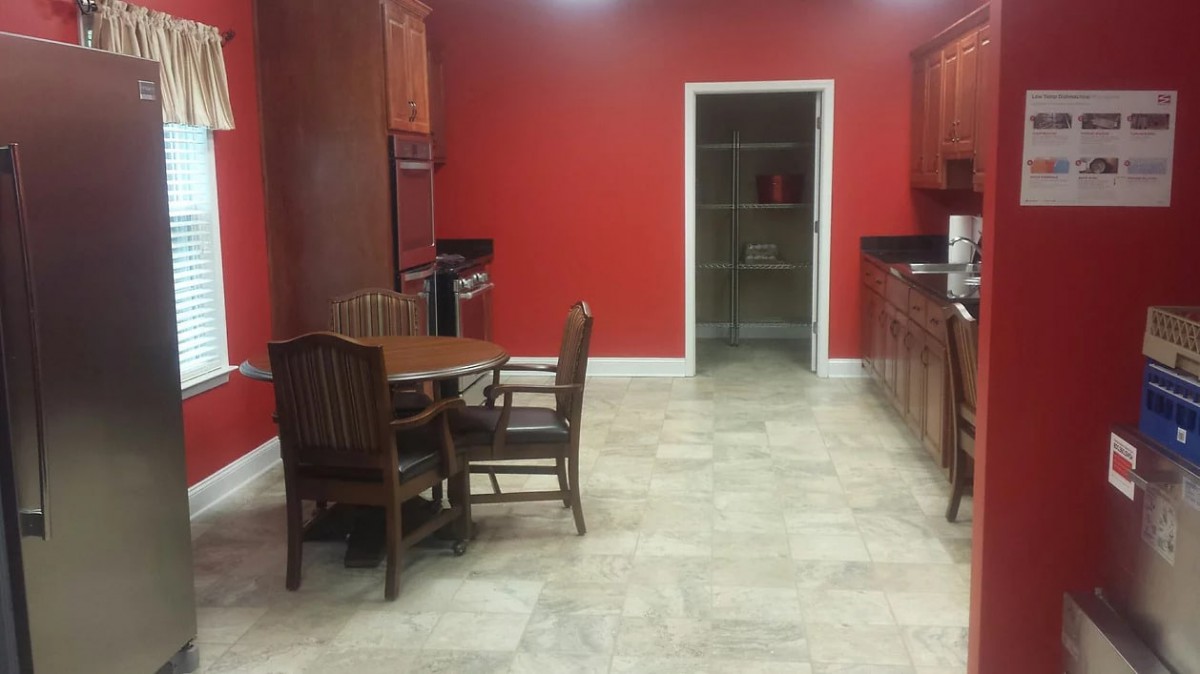 A kitchen with red walls, wooden furniture, and a tile floor.