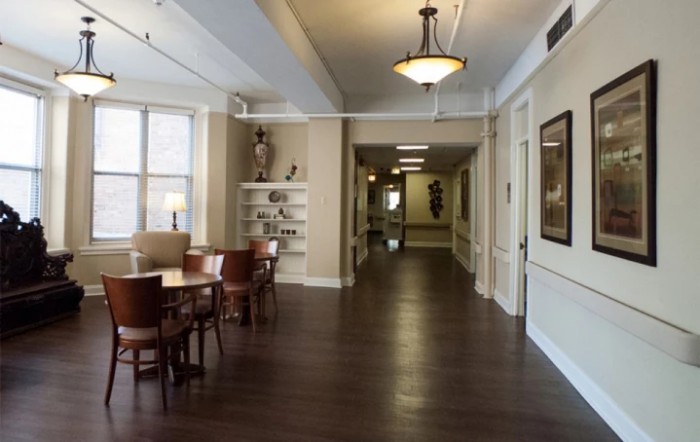 A well-lit interior hallway with wooden flooring, featuring a seating area and decorative elements.