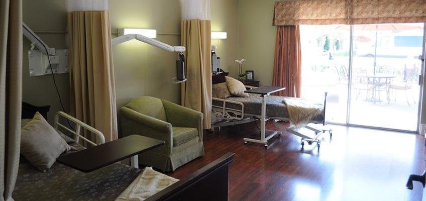 A hospital room featuring a medical bed, chair, and healthcare equipment.