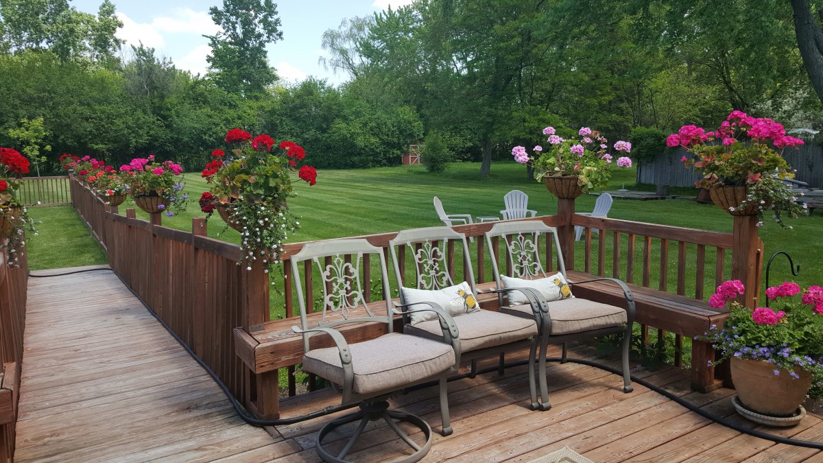 An inviting outdoor patio with cushioned chairs and flowering plants overlooking a lush garden.
