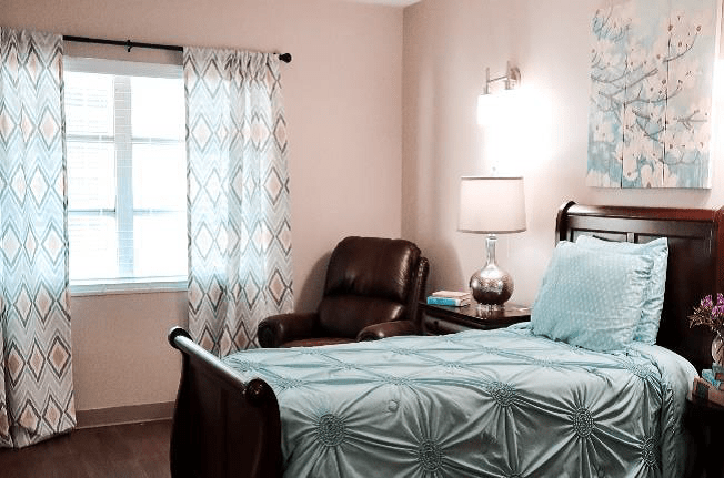 A modern bedroom with a neatly made bed, armchair, and stylish decor.