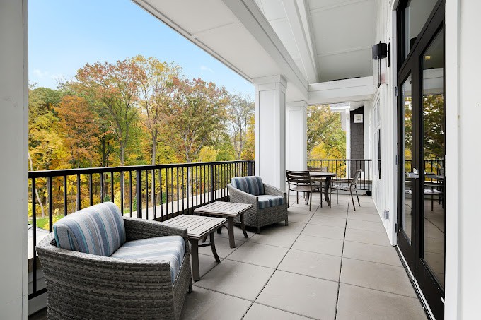A spacious balcony with comfortable outdoor seating and a scenic view of trees.