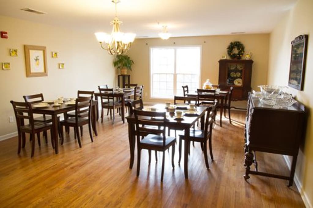 A well-lit dining area with multiple wooden tables and chairs, featuring a cozy interior design.