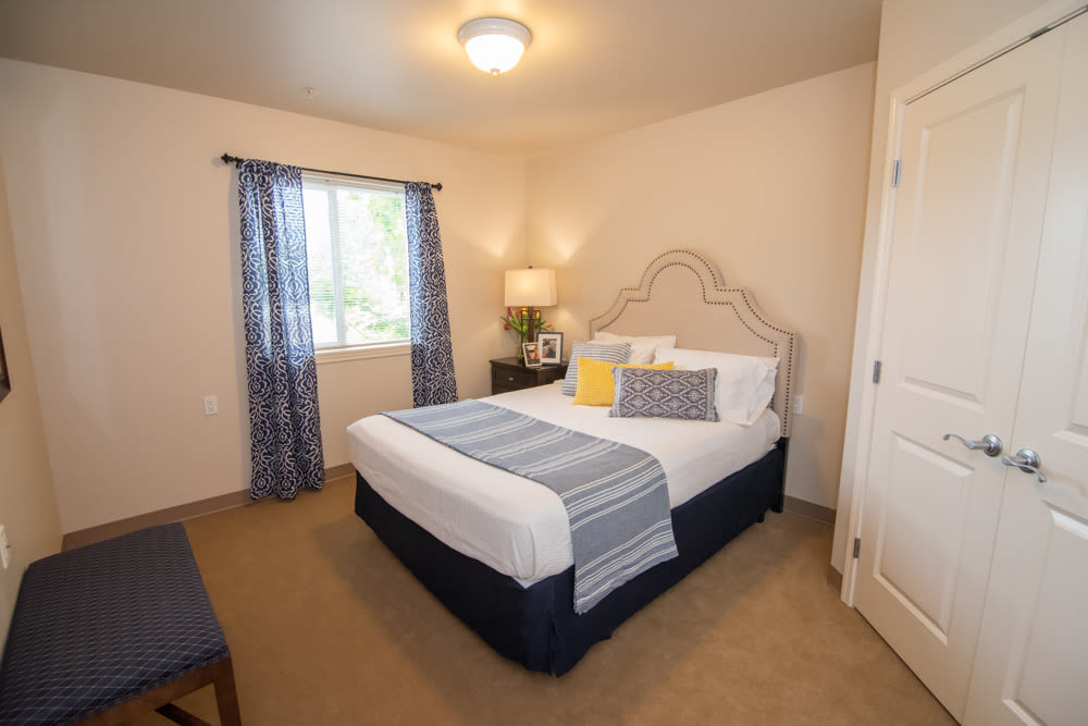 A cozy bedroom with a neatly made bed, soft lighting, and a window adorned with curtains.