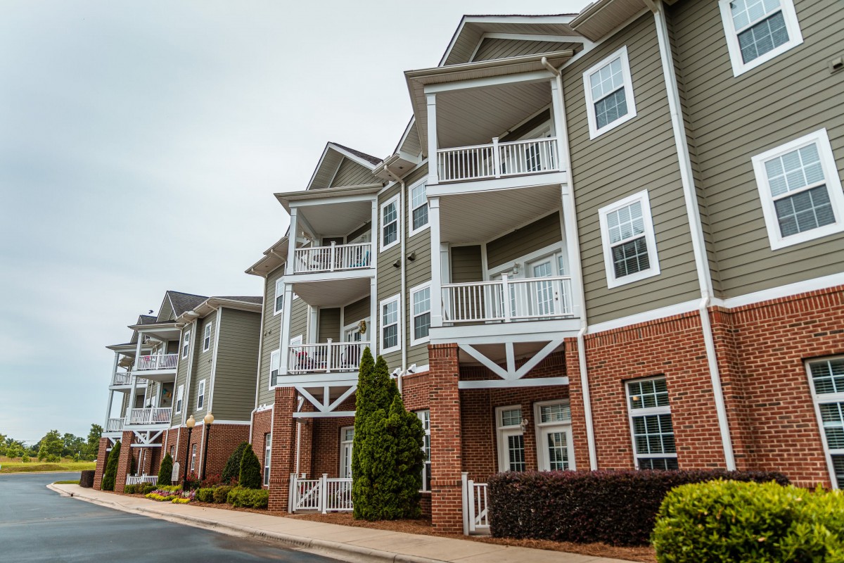 A modern apartment building with balconies, featuring a combination of brick and siding exterior.