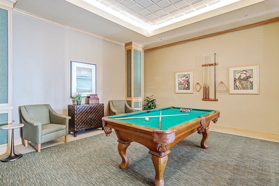 A cozy game room featuring a pool table, comfortable seating, and decorative artwork.