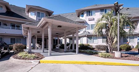 A residential building with a covered entrance and landscaped surroundings.