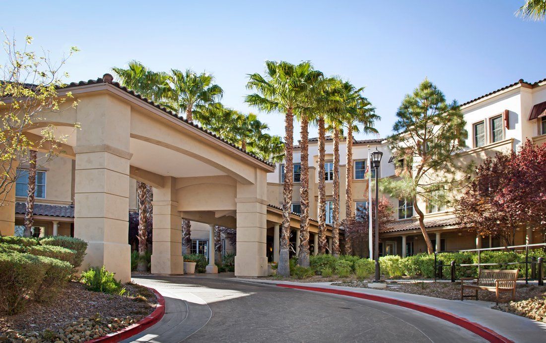 A hotel entrance surrounded by tall palm trees and landscaped gardens.
