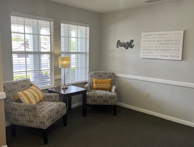 A cozy corner of a living room with two patterned chairs, a small lamp, and decorative pillows.