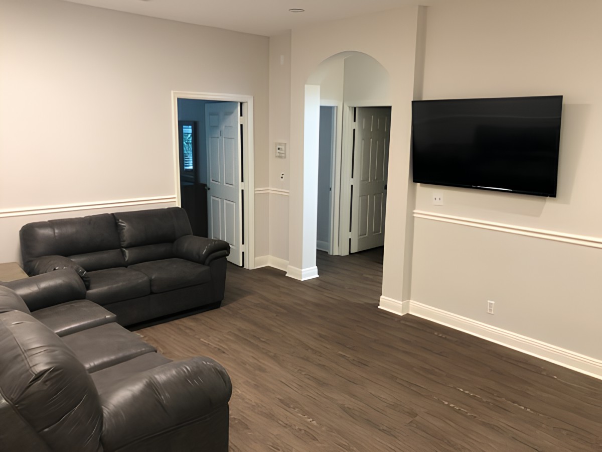 A modern living room with a leather couch, wall-mounted TV, and wood flooring.