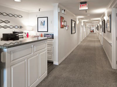 A modern interior hallway with a reception desk and framed art on the walls.