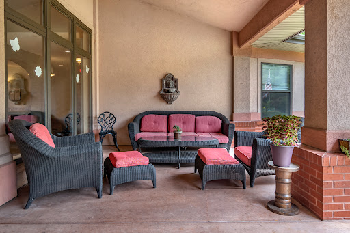 A cozy outdoor patio setup featuring wicker furniture with pink cushions, perfect for relaxation.