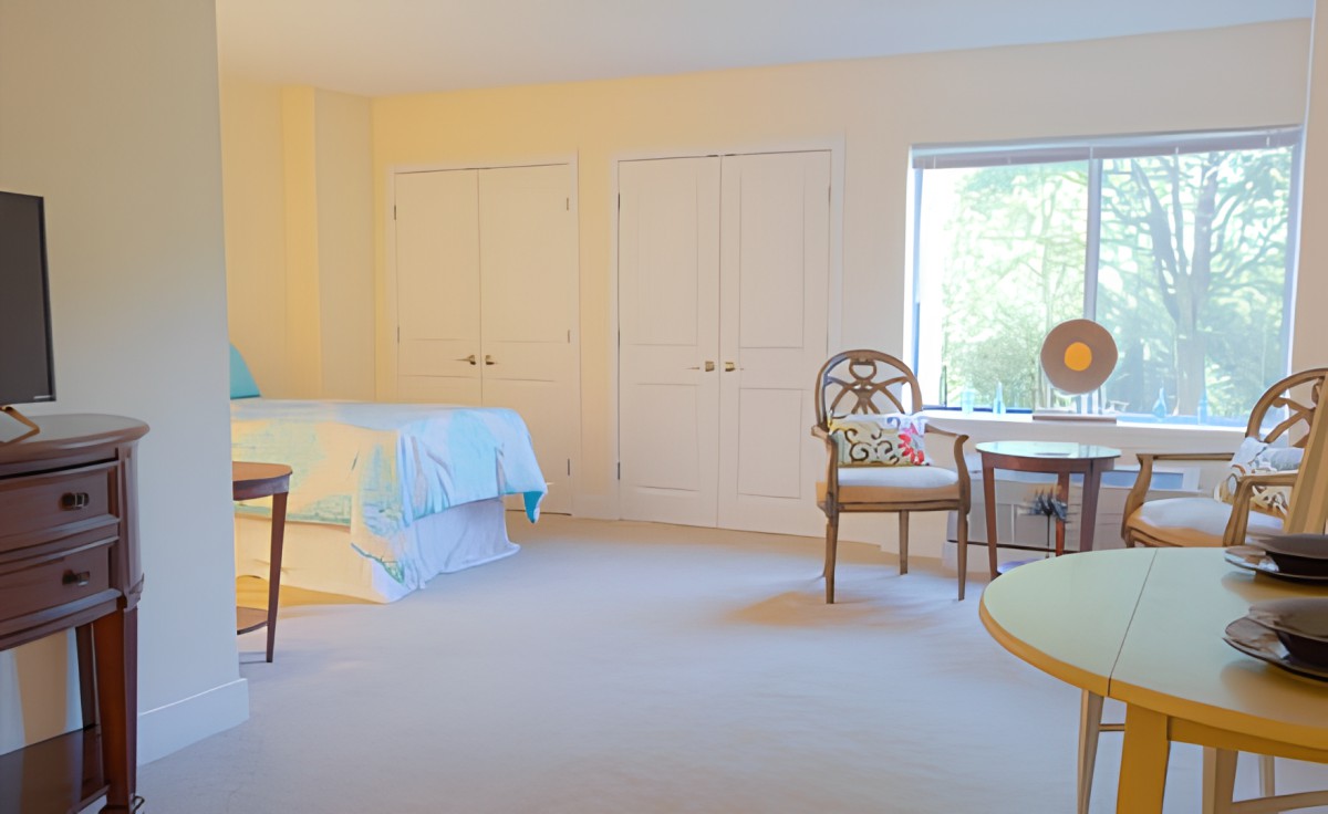 A cozy bedroom with a bed, chairs, and a table near a window.