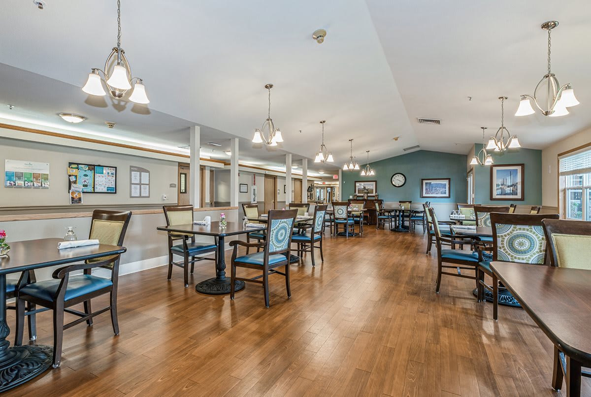 A spacious dining area with elegant lighting and neatly arranged tables on a hardwood floor.