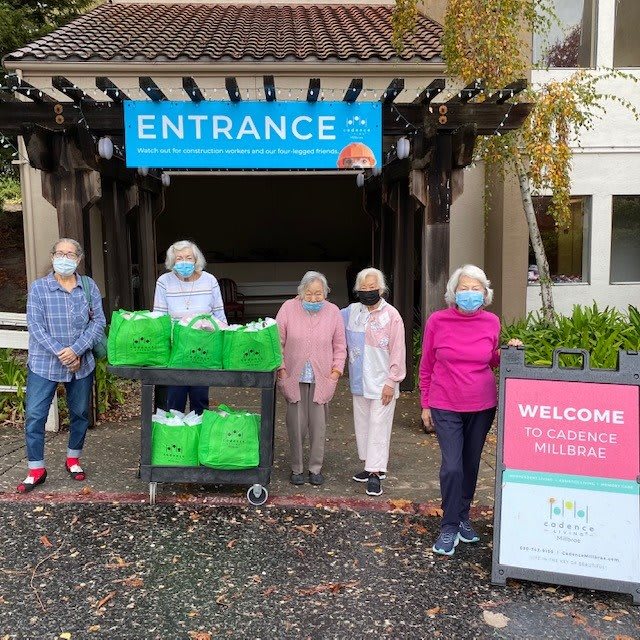 A group of volunteers standing by an entrance with donation bags, all wearing masks.