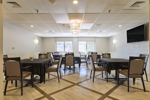 A spacious indoor dining area set up with tables and chairs, illuminated by natural light.