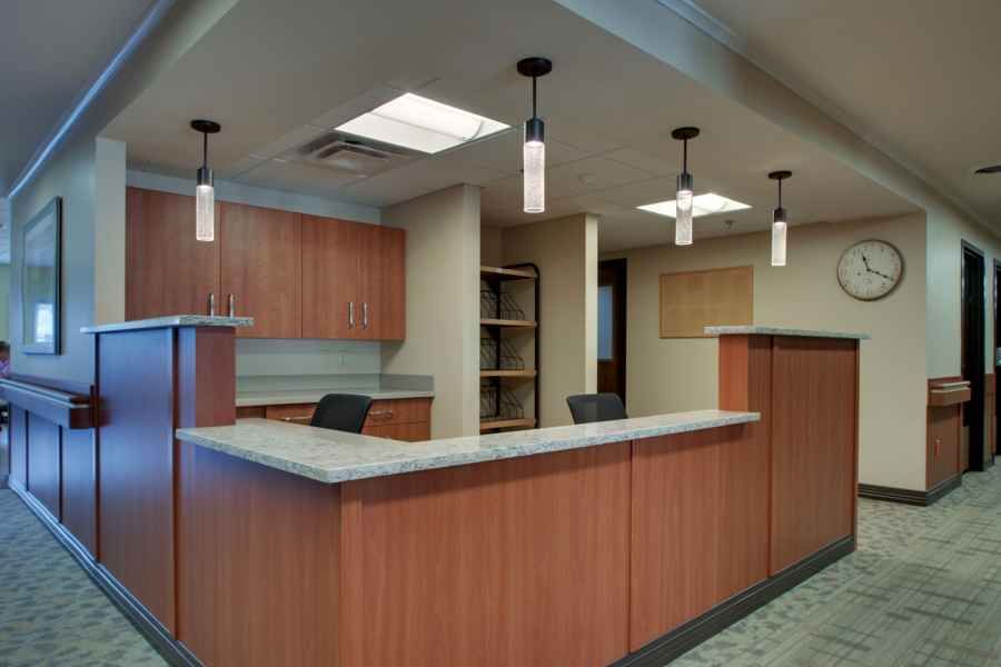 Modern office reception area with wooden desks and pendant lighting.