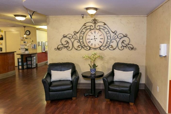 A cozy lobby area featuring two leather chairs and a decorative wall clock.