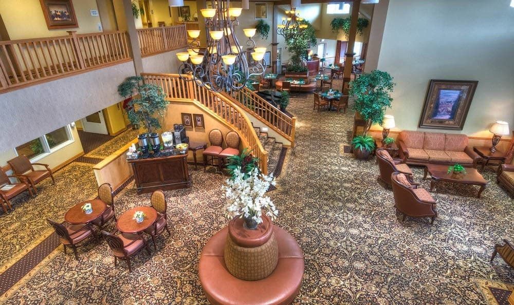 A spacious hotel lobby featuring a grand staircase, cozy seating areas, and elegant lighting.