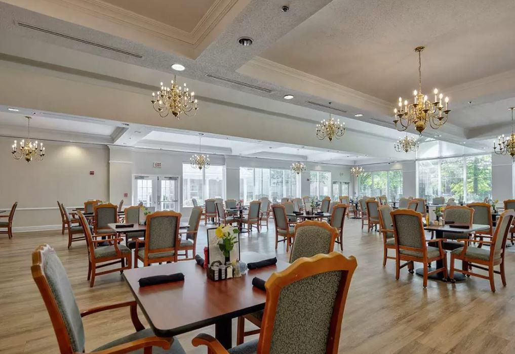 A spacious and elegantly decorated dining hall with chandeliers, featuring neatly arranged tables and chairs.