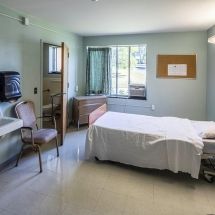 A clean and organized hospital room with a bed, chair, and window.