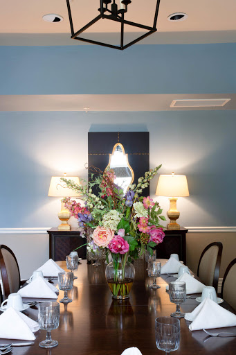 A beautifully arranged dining room featuring a vibrant floral centerpiece and elegant table settings.