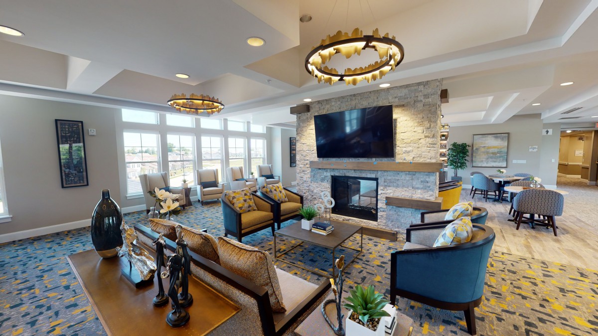 A modern and spacious living room featuring a stone fireplace, large TV, and stylish furnishings.